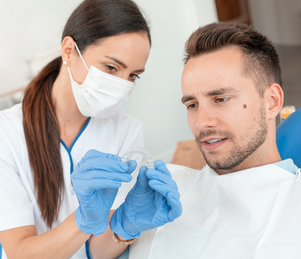 Dentist shows invisible braces aligner oral appliance to patient