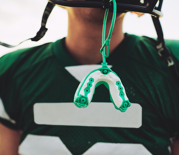 sportsguard/Mouthguard hanging off helmet of football player | Oral appliances | My Dental Advocate