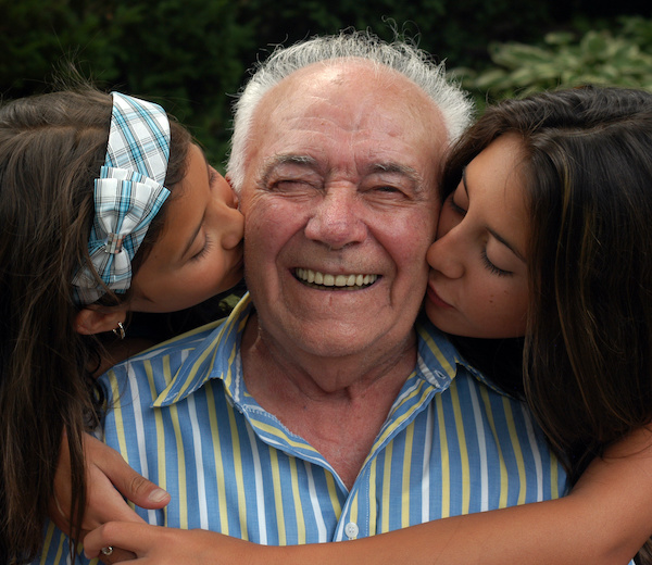 What are dentures | Smiling grandfather being kissed by granddaughters