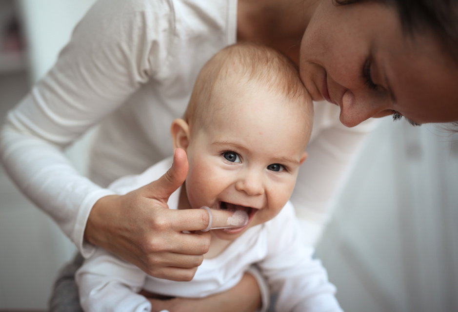 Mom cleaning baby teeth | Baby Teething: Signs, Symptoms & Solutions | My Dental Advocate