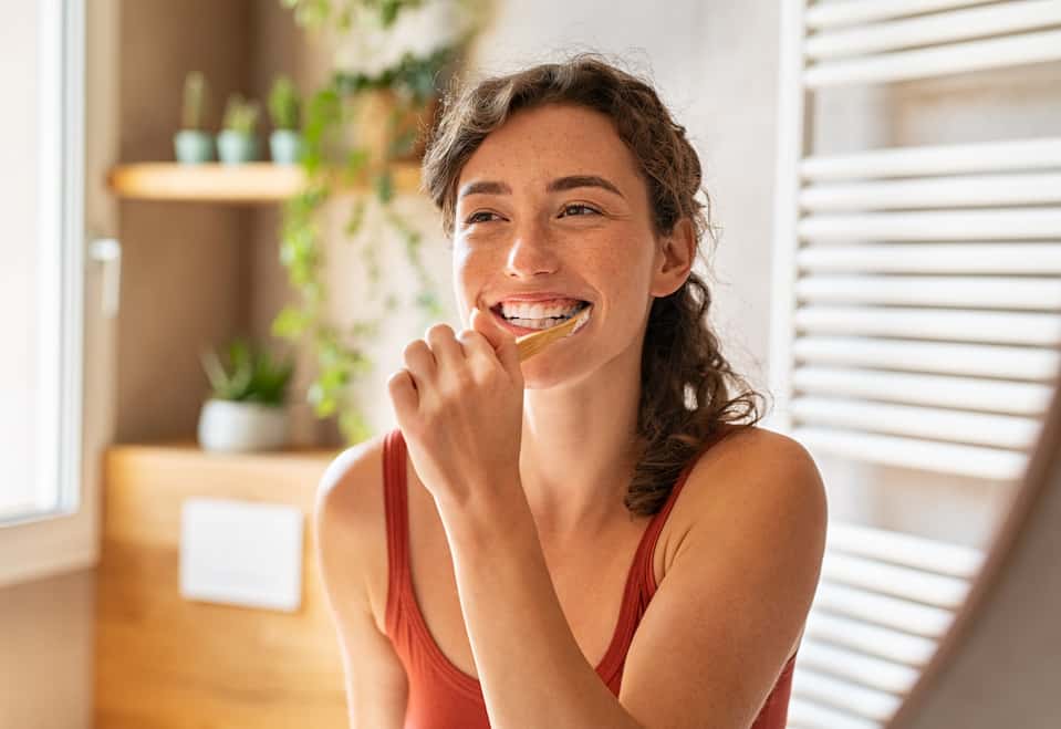 Woman Brushing Teeth In Mirror | My Dental Advocate